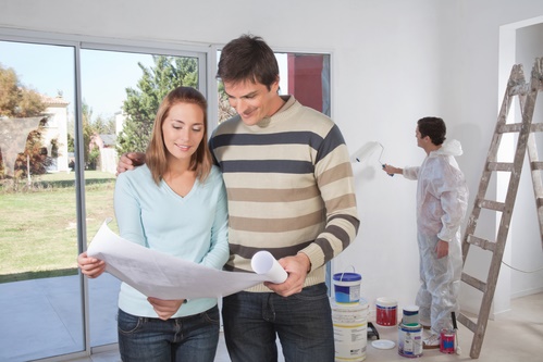 Couple going through house plan while painter in the background